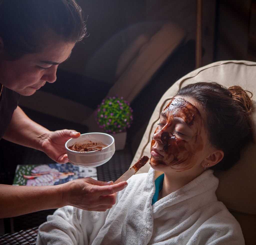 Side vew chocolate mask with woman and master on beauty saloon background